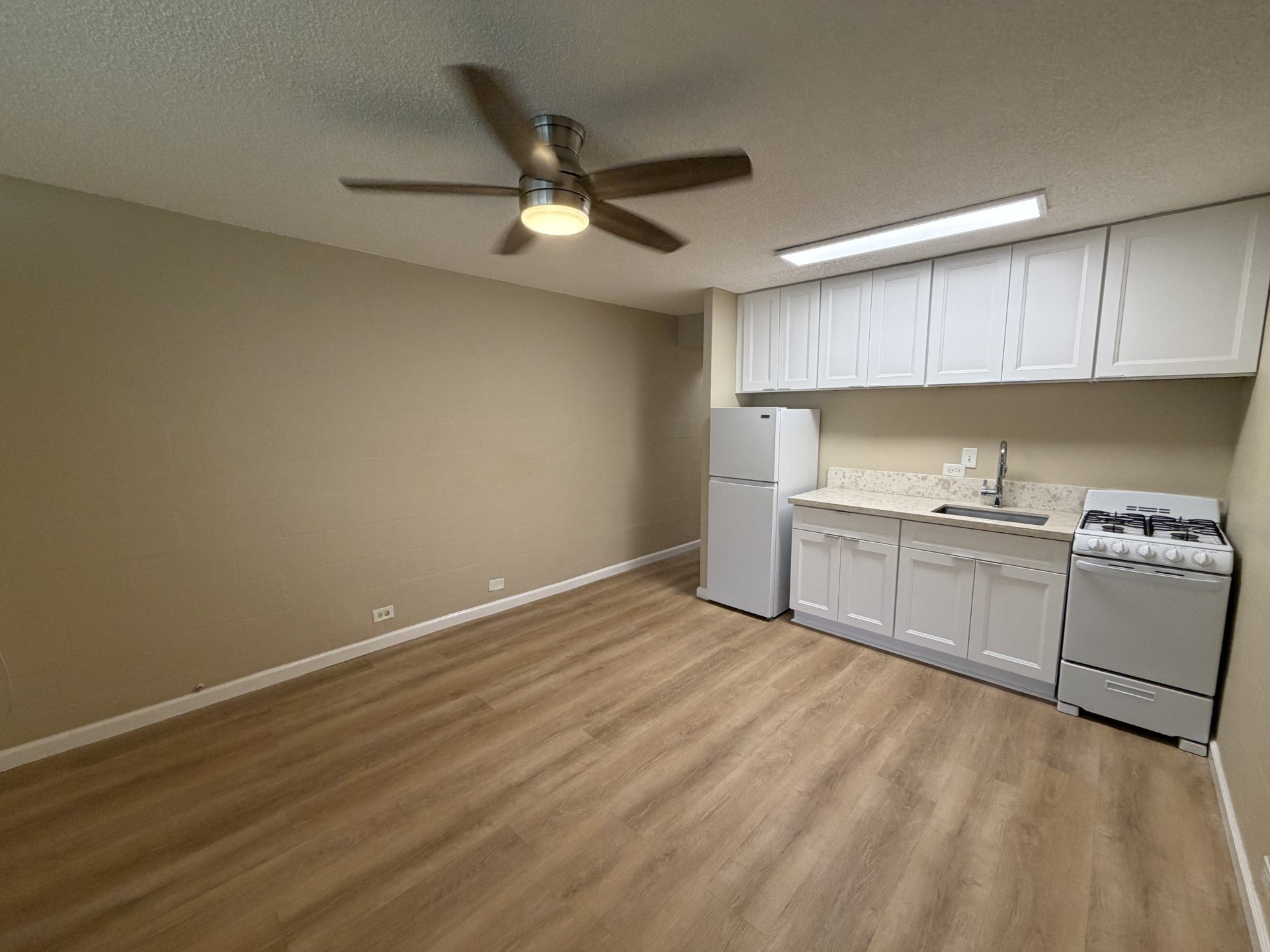 A kitchen with a stove, refrigerator, and cabinets.
